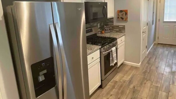A modern kitchen with stainless steel appliances, white cabinetry, and a herringbone wood floor. - Perfect Oasis. NEW Home Away from Home with COVERED PARKING-Close to everything (Stillwater)