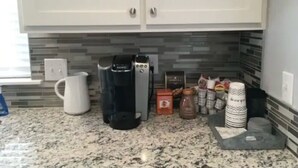 A kitchen with a coffee maker, a white pitcher, and various kitchen items on the counter. - Perfect Oasis. NEW Home Away from Home with COVERED PARKING-Close to everything (Stillwater)