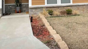 A residential house with a brick roof, a front porch, and a small garden area with mulch and plants. - Perfect Oasis. NEW Home Away from Home with COVERED PARKING-Close to everything (Stillwater)