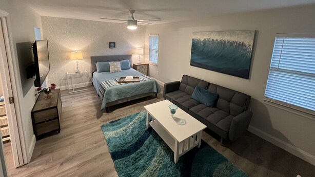Ein Schlafzimmer mit einem Bett, Nachttischlampen, einem Fernseher, einem Deckenventilator und einem Bild an der Wand.