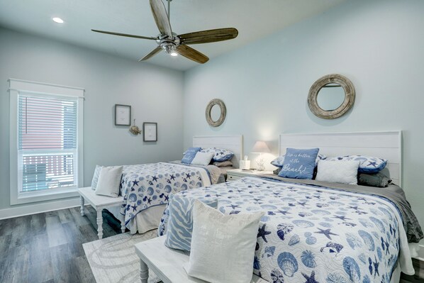 A bedroom with two beds, a ceiling fan, and a window with blinds.