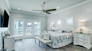Une chambre à coucher comprenant un lit, un banc, une table de chevet et un ventilateur de plafond.