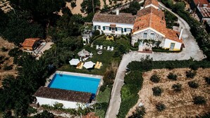 An aerial view of a large estate with a swimming pool, multiple buildings, and a well-maintained garden.