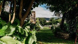 A garden with a stone bench, a tree, and a view of a distant building.