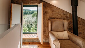 A cozy room with a stone wall, a large window, a sofa, and a chimney.