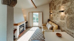 Un salon chaleureux avec un mur en pierre, une cheminée, un canapé et une table à manger.