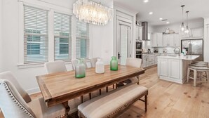 Een moderne keuken met witte kasten, een houten eettafel en een centraal eiland.