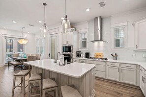 A modern kitchen with a central island, stainless steel appliances, and pendant lighting.