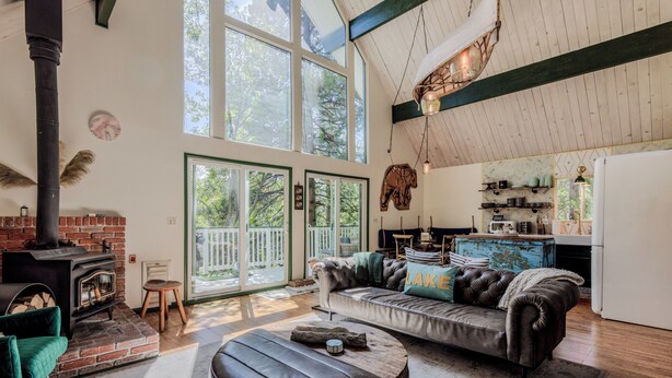 Una sala de estar acogedora con chimenea, sofá de cuero y un ventanal con vistas a una terraza.