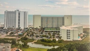 Een hotelcomplex aan de kust met meerdere hoge gebouwen, een parkeerplaats en een waterpartij.