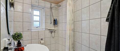 Un baño con lavamanos blanco, ducha y ventana.