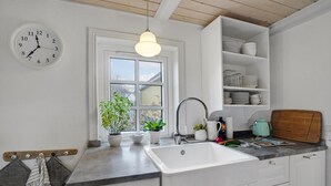 A kitchen with a white sink, a clock, and a window with plants. - 3 bedroom gorgeous home in Vestervig (Vestervig)
