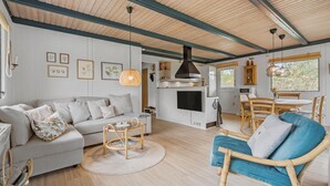 A cozy living room with a sofa, a blue armchair, a small round table, and a TV. - 3 bedroom awesome home in Skjern (Skjern)