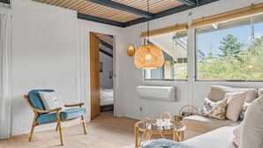 A spacious living room with a large window, a sofa, a chair, and a table with a lamp. - 3 bedroom awesome home in Skjern (Skjern)