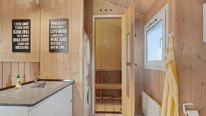 Un interior de madera con cocina, lavadora y baño con ducha.