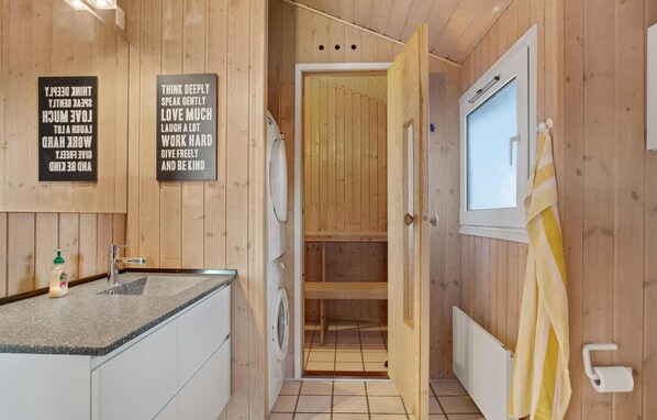 Un intérieur en bois comprenant un coin cuisine, un lave-linge et une salle de bain avec douche.
