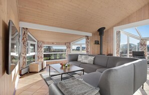 Relax in this stylish living area with a large sofa, coffee table, and wicker chair, offering a view of the outdoors.