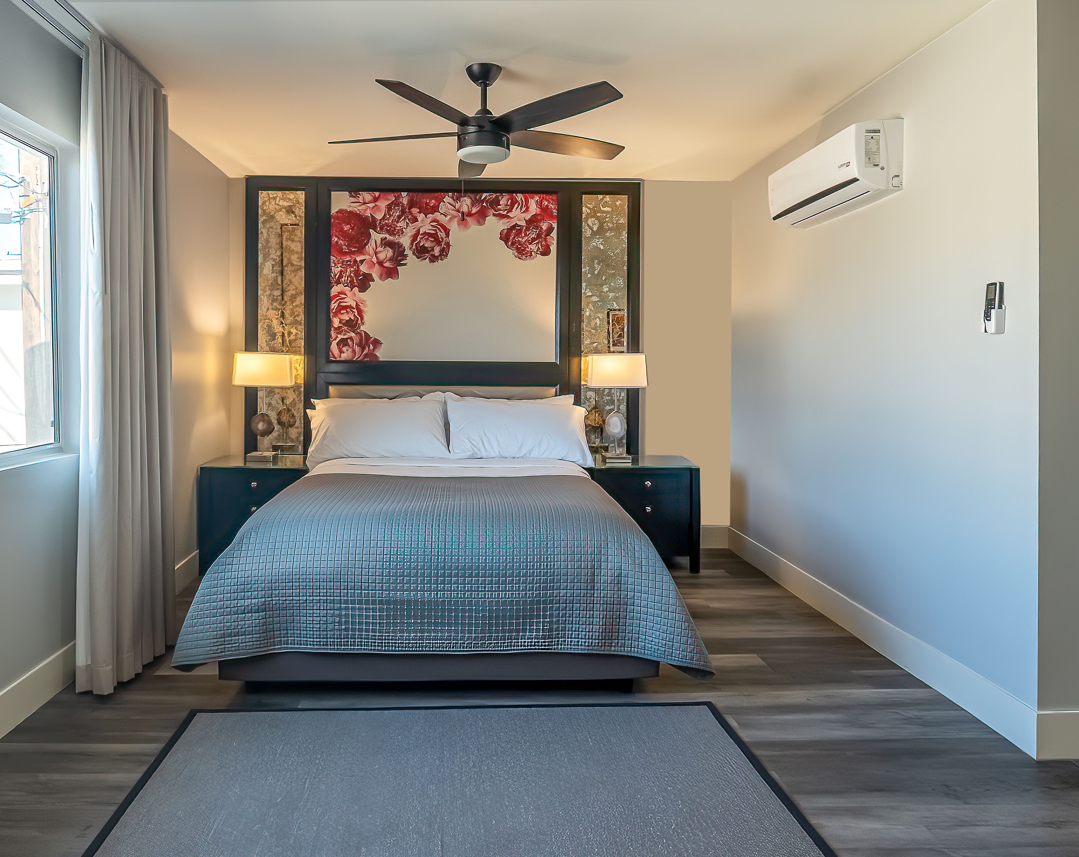 A neatly arranged bedroom with a bed, two bedside tables, a ceiling fan, and an air conditioning unit.