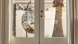A room with a sliding glass door, a woven chair, a dog bed, and a metal bowl on the floor. - Onsen Hotel & Spa (Desert Hot Springs)