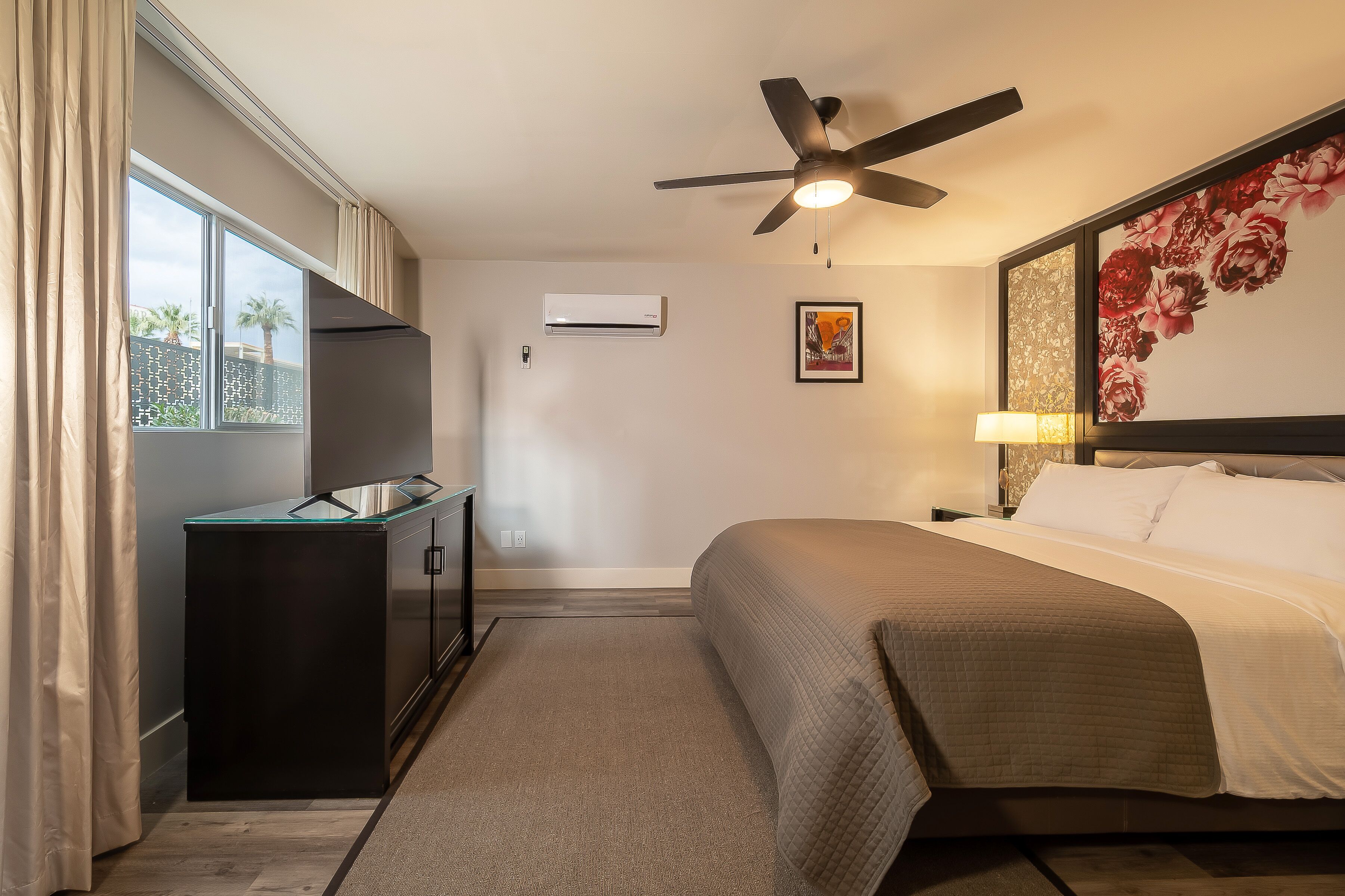 Une chambre d’hôtel équipée d’un lit, d’un ventilateur de plafond, d’une télévision et d’un appareil de climatisation.