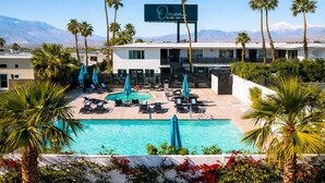 A hotel with a pool, palm trees, and mountains in the background. - Onsen Hotel & Spa (Desert Hot Springs)