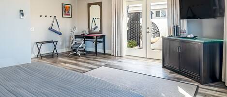 A hotel room with a bed, desk, chair, and a view of the outside.
