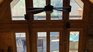 Een chalet met een groot houten plafond, een plafondventilator en uitzicht op een zwembad en bergen.