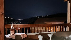 Een hottub met een houten terras en een tafel met een fles en glazen.