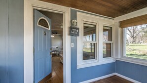 Une pièce avec une porte bleue, une fenêtre donnant sur l’extérieur et un panneau indiquant « Bienvenue ».