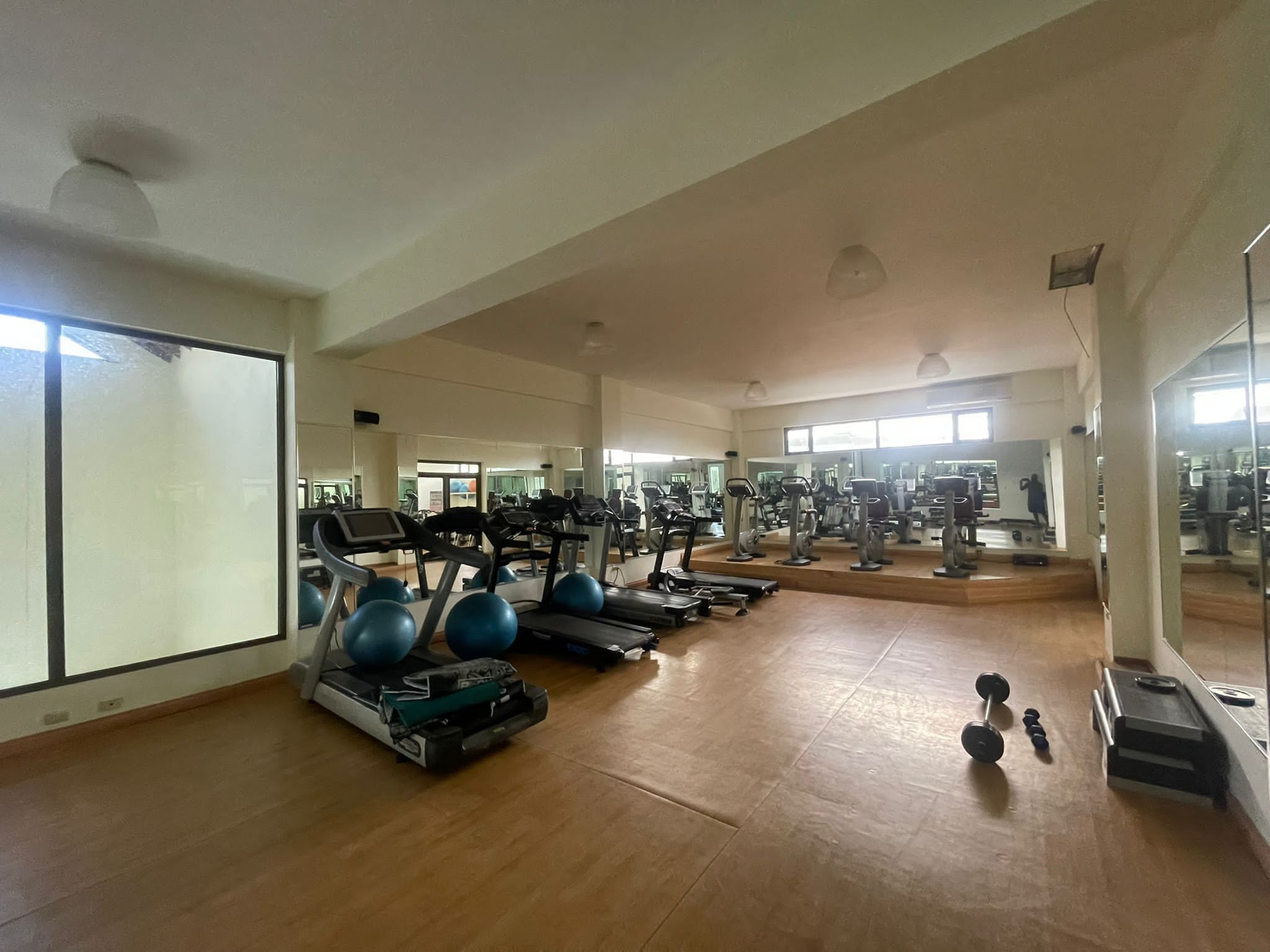 A spacious gym with cardio machines, weightlifting equipment, and mirrors.