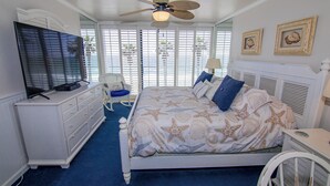 Une chambre à coucher comprenant un lit, une commode, un téléviseur et un ventilateur de plafond.