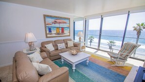 Un salon avec vue sur la plage, comprenant un canapé, une table basse et un fauteuil.