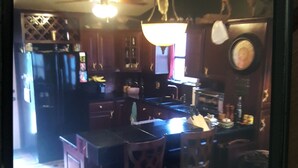 Una cocina con armarios de madera, un refrigerador, un lavamanos y una zona de comedor con sillas.
