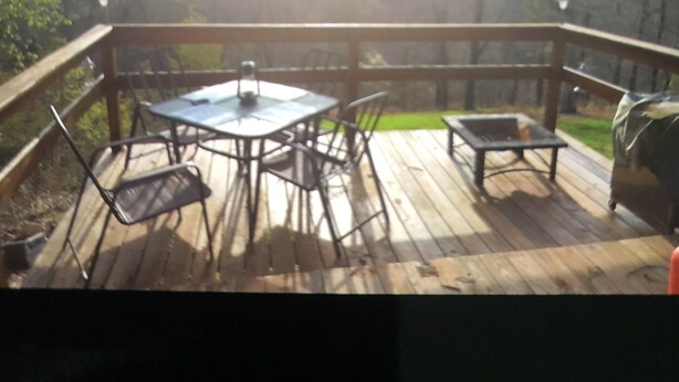 Una terraza de madera con una mesa y sillas, rodeada por barandas de madera.