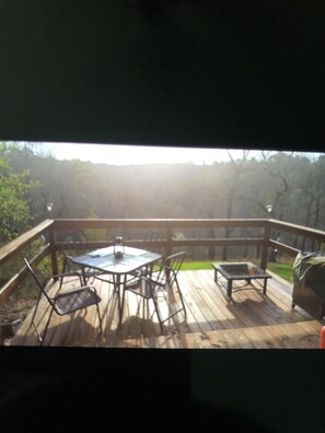 A wooden deck with a table and chairs, surrounded by a wooden railing.