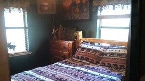 Un dormitorio con cama, cómoda, ventilador de techo y ventana con cortinas.