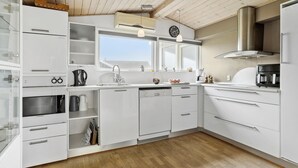 A modern kitchen with white cabinetry, a built-in oven, a coffee machine, and a window above the sink. - 3 bedroom amazing home in Spøttrup (Spøttrup)