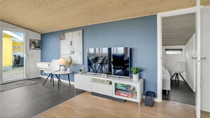 A modern living room with a large flat-screen TV, a white console table, and a blue accent wall. - 3 bedroom amazing home in Spøttrup (Spøttrup)