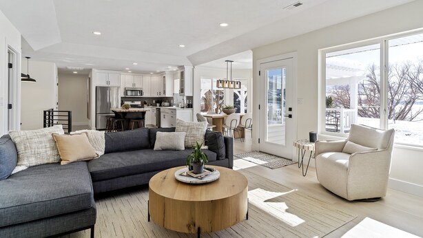 A modern living room with a grey sofa, a round coffee table, and a beige armchair.