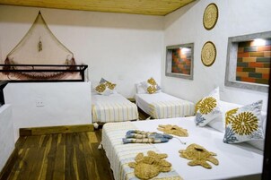 Una habitación con dos camas, una hamaca colgante y paneles decorativos en las paredes.