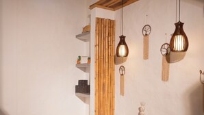 A massage therapy room with a treatment table, a wall-mounted fan, and decorative wall hangings. - HONDA COLONIAL MAGDALENA RESORT (Honda)