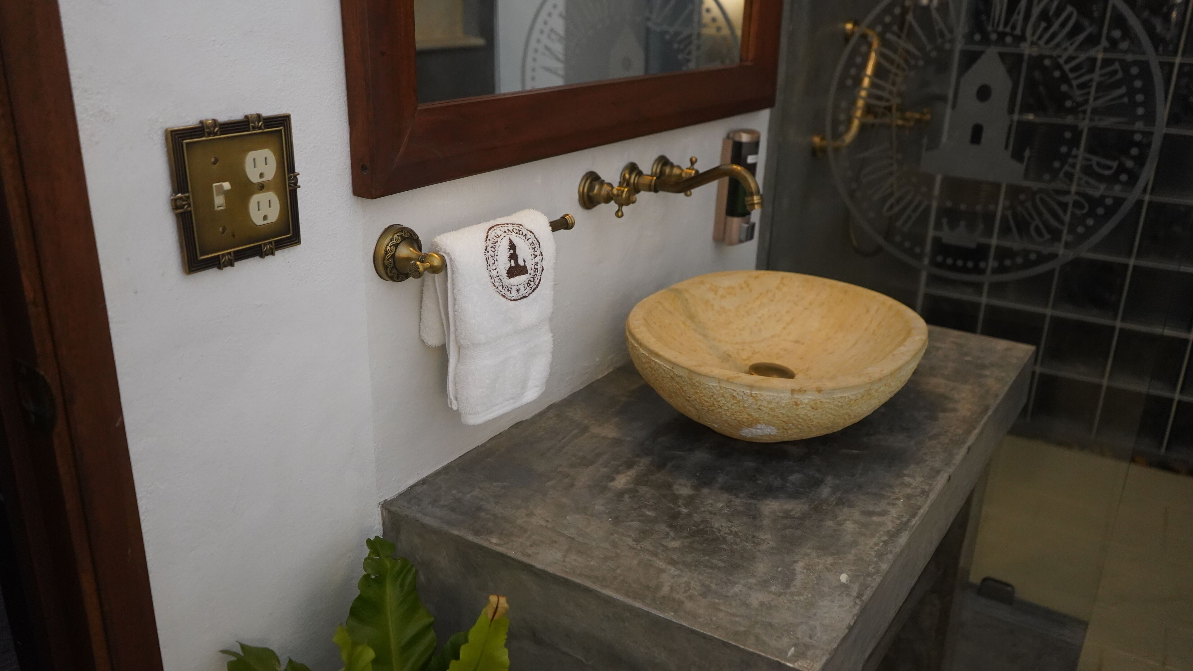Un baño con un lavabo de piedra, una toalla colgada en un perchero y un espejo sobre el lavabo.