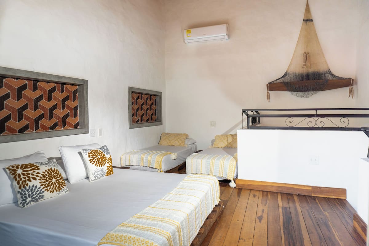 A room with two beds, a hanging light fixture, and a patterned wall decoration.