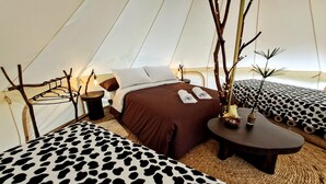 Een gezellig ingerichte tent met een bed, een klein tafeltje en een stoel.