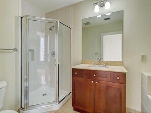 A bathroom with a glass-enclosed shower, a wooden vanity with a sink, and a mirror above the vanity.