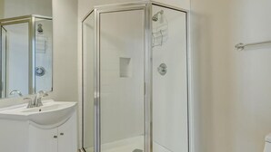 A modern bathroom with a glass-enclosed shower, a white sink, and a mirror. - Popular Filming Area- Downtown Atlanta Condo (atlanta)