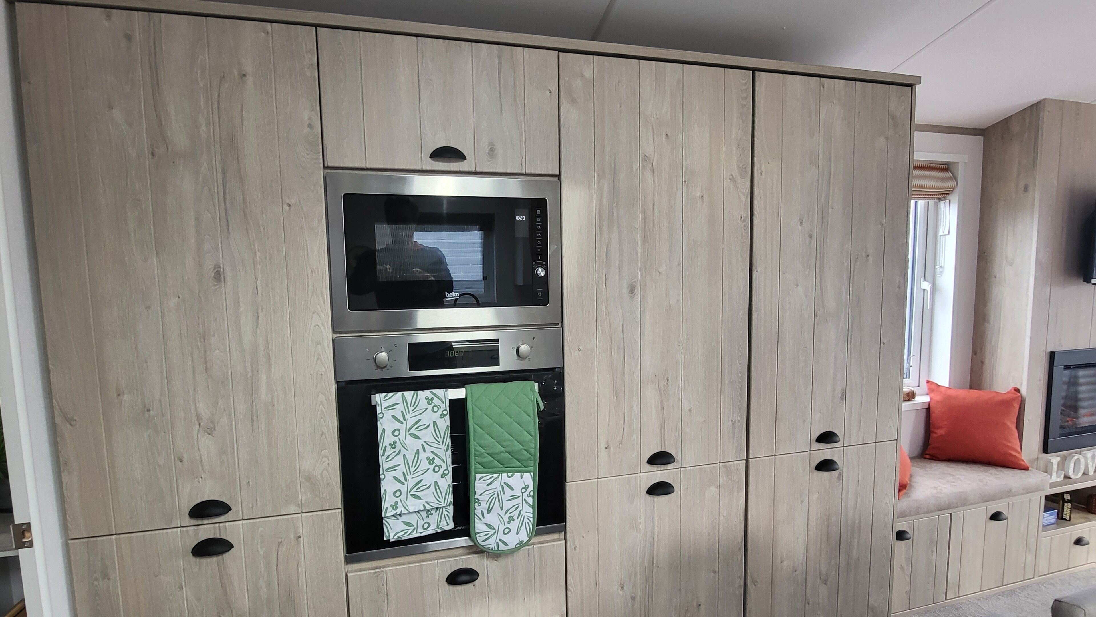 Una cocina con armarios de madera, un microondas y un horno empotrado.
