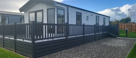 A mobile home with a black deck and a gravel driveway.