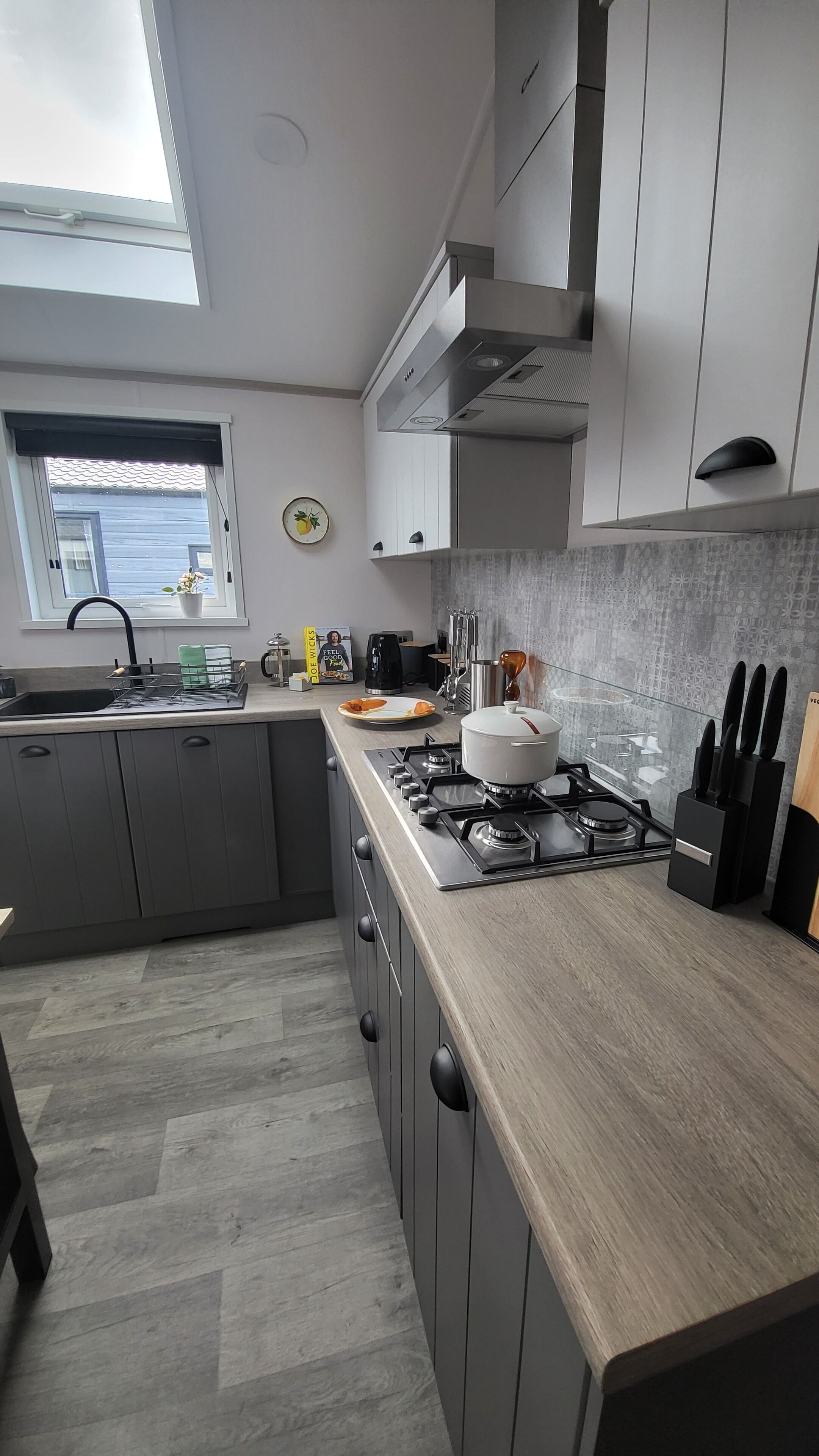A modern kitchen with grey cabinets, a stainless steel stove, and a window with a view of the outside.
