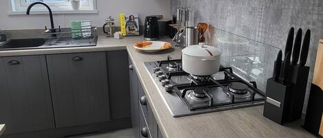 A modern kitchen with grey cabinets, a stainless steel stove, and a window with a view of the outside.